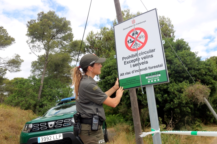 A rural officer placing a poster with prohibited activities in Montgrí's natural park on July 7, 2022 (by Xavier Pi)